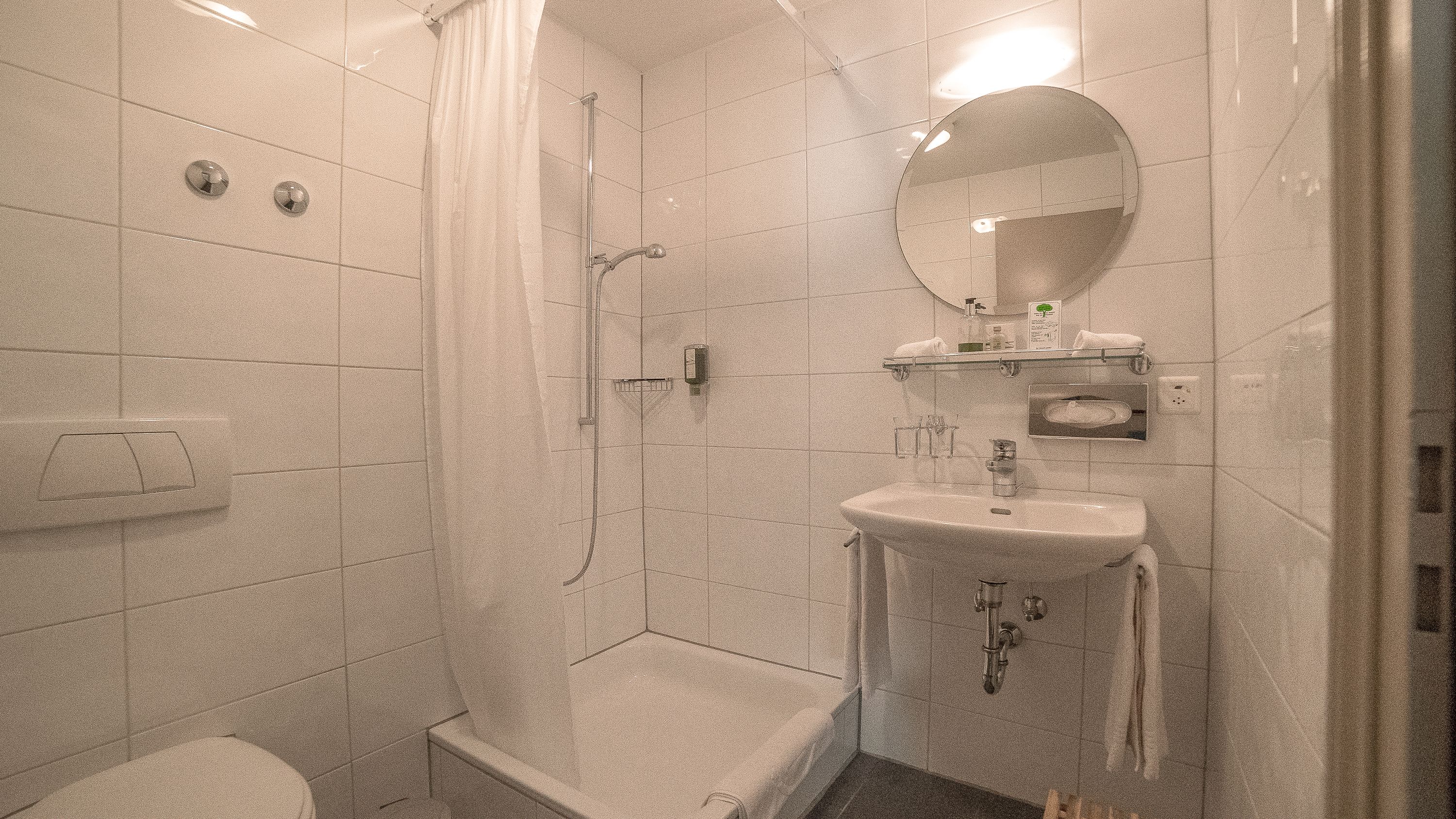 A bathroom with a shower, toilet, sink, and a mirror.