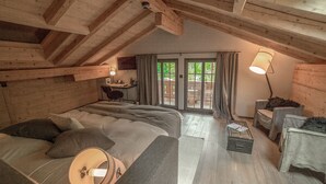 A cozy attic bedroom with a bed, a desk, and a chair. There is a window with curtains and a view of greenery outside. - Hotel Blausee (Kandergrund)