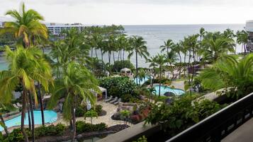Un resort con varias piscinas rodeado de palmeras y vista al océano.