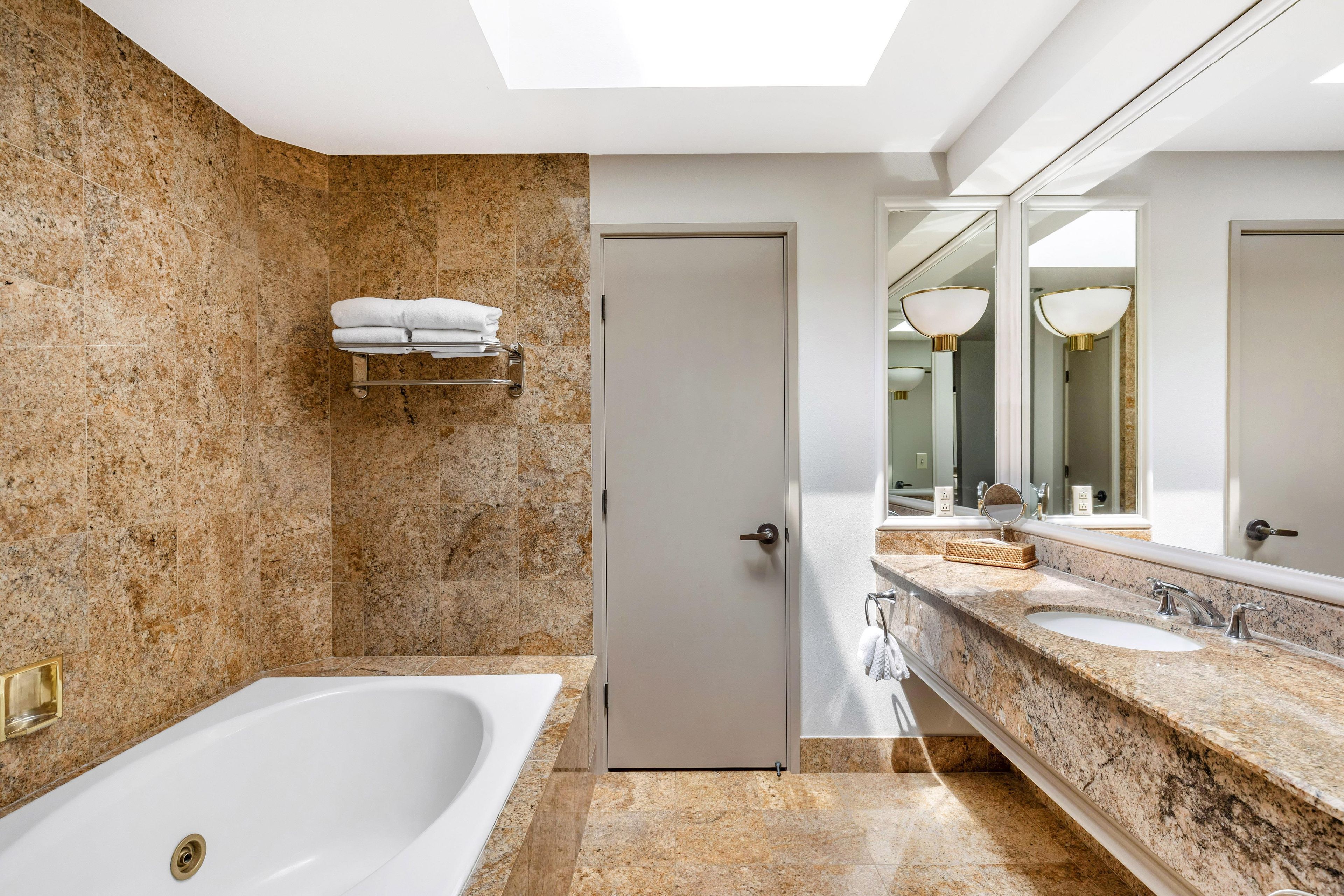 A modern bathroom with a freestanding bathtub, a vanity with a large mirror, and a towel rack.