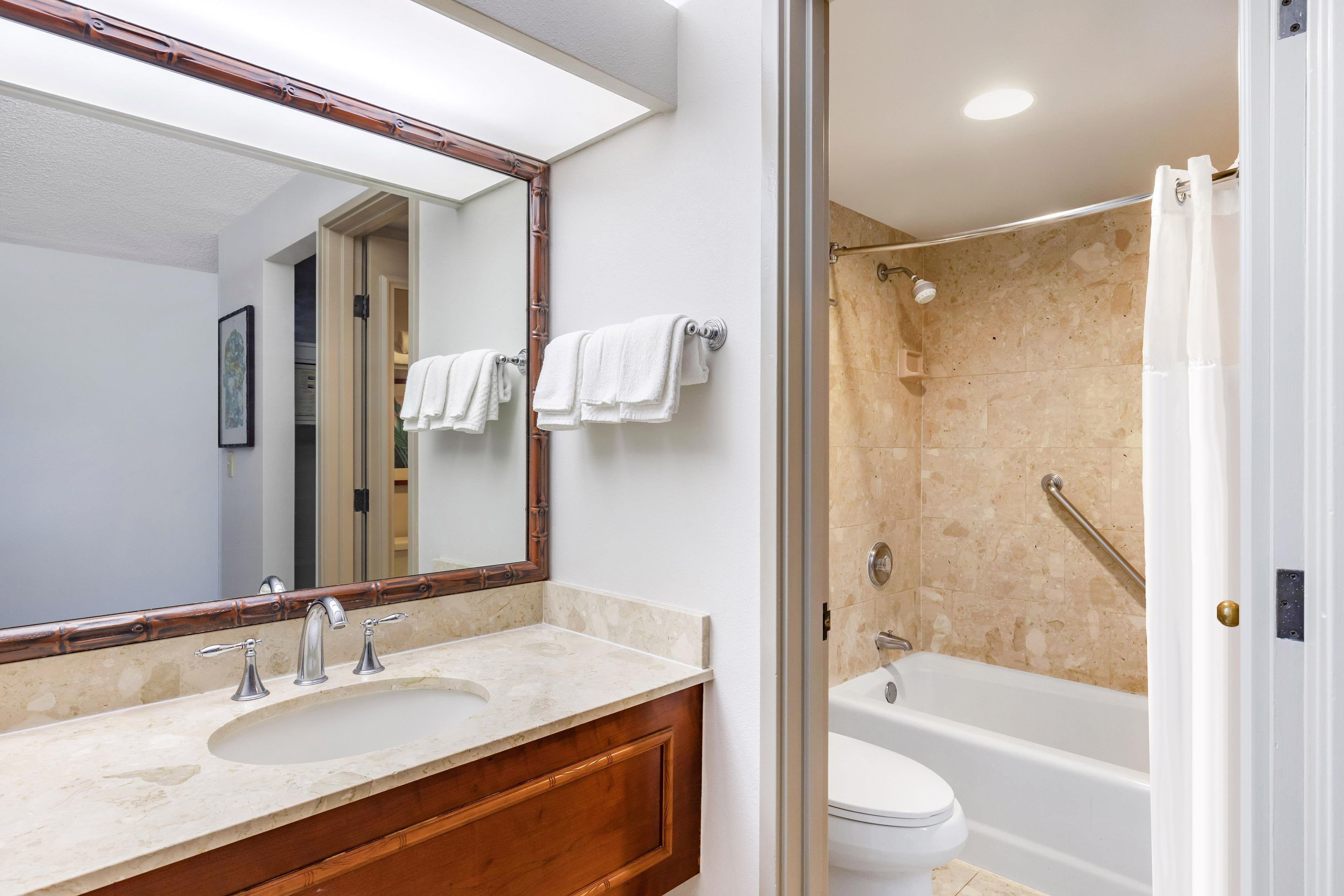 Une salle de bain avec un grand miroir, un lavabo à deux robinets et une baignoire.
