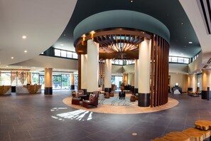 A spacious lobby with a central seating area, large windows, and a distinctive wooden column structure.