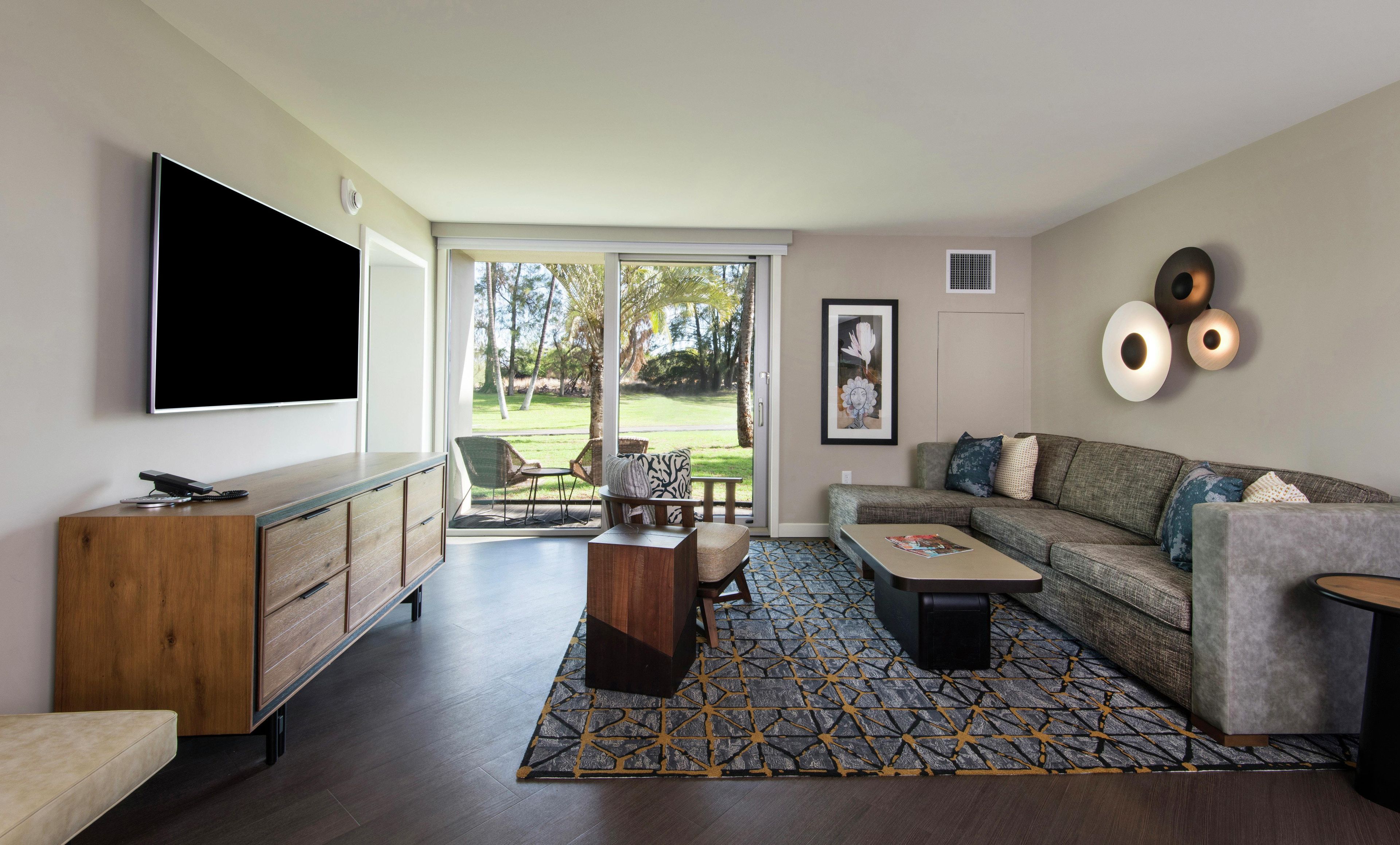 Una sala moderna con una televisión de pantalla plana, un sofá, una mesa de centro y una alfombra estampada.