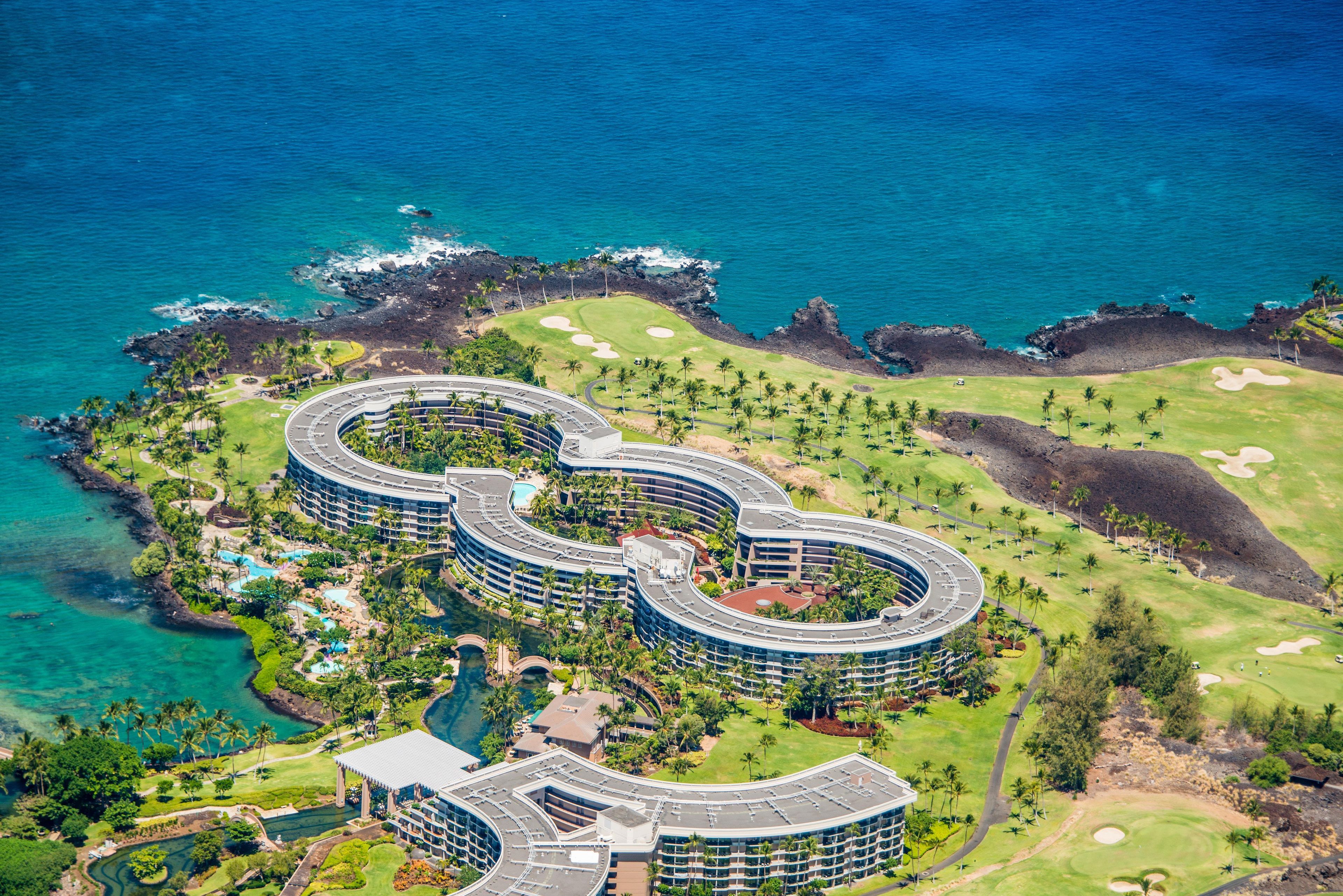 A resort with a circular building layout, a golf course, and a coastline.
