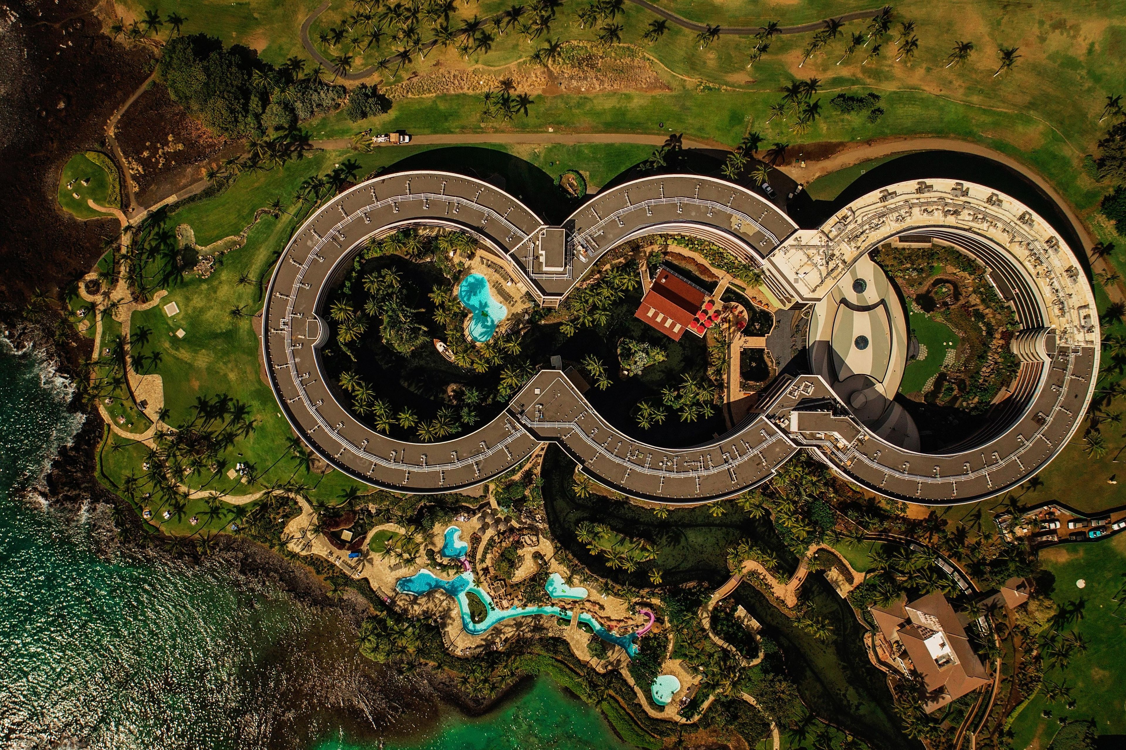 A large resort with multiple swimming pools, a central building, and a surrounding road.