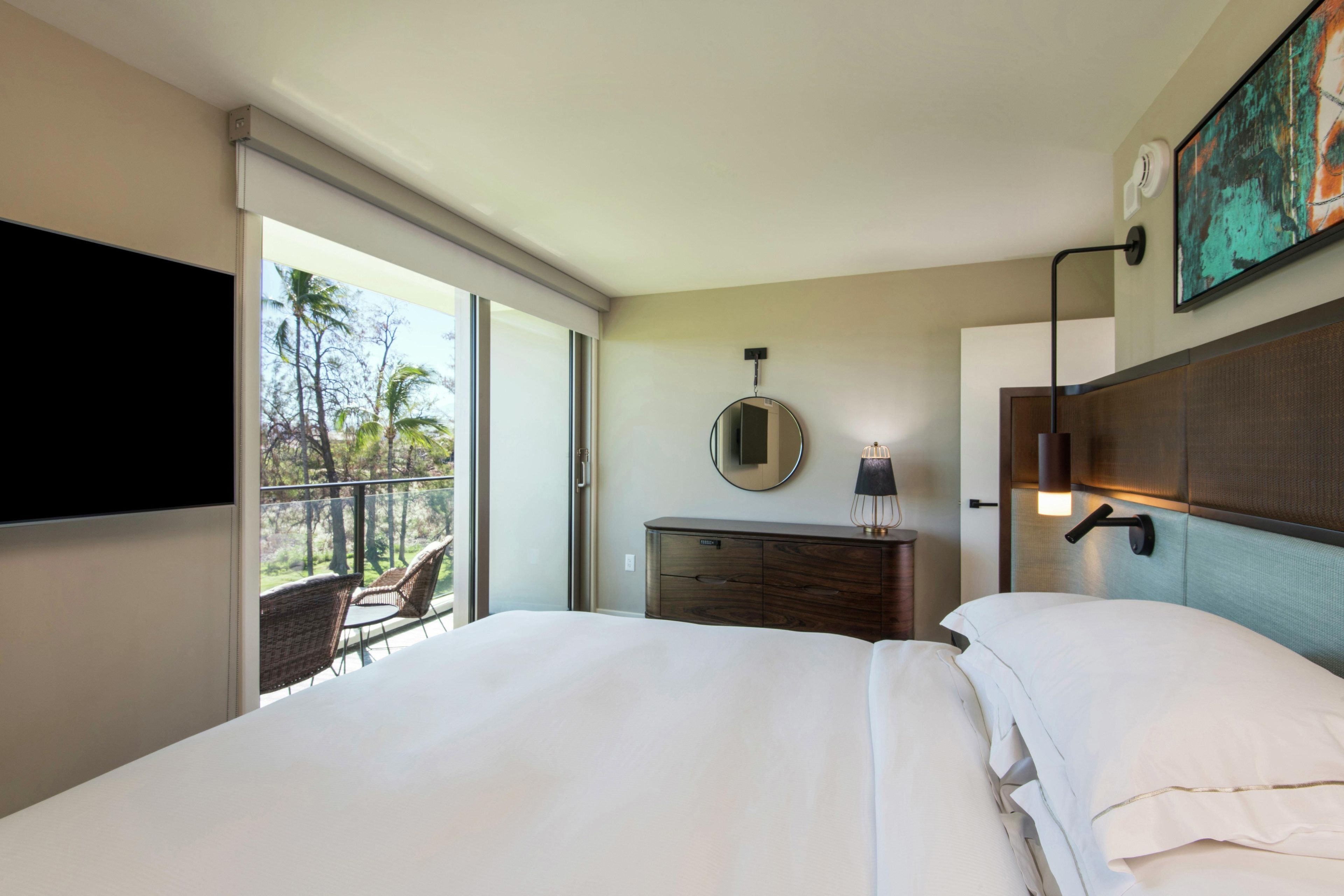Een hotelkamer met een bed, een dressoir, een spiegel, een lamp en een televisie.
