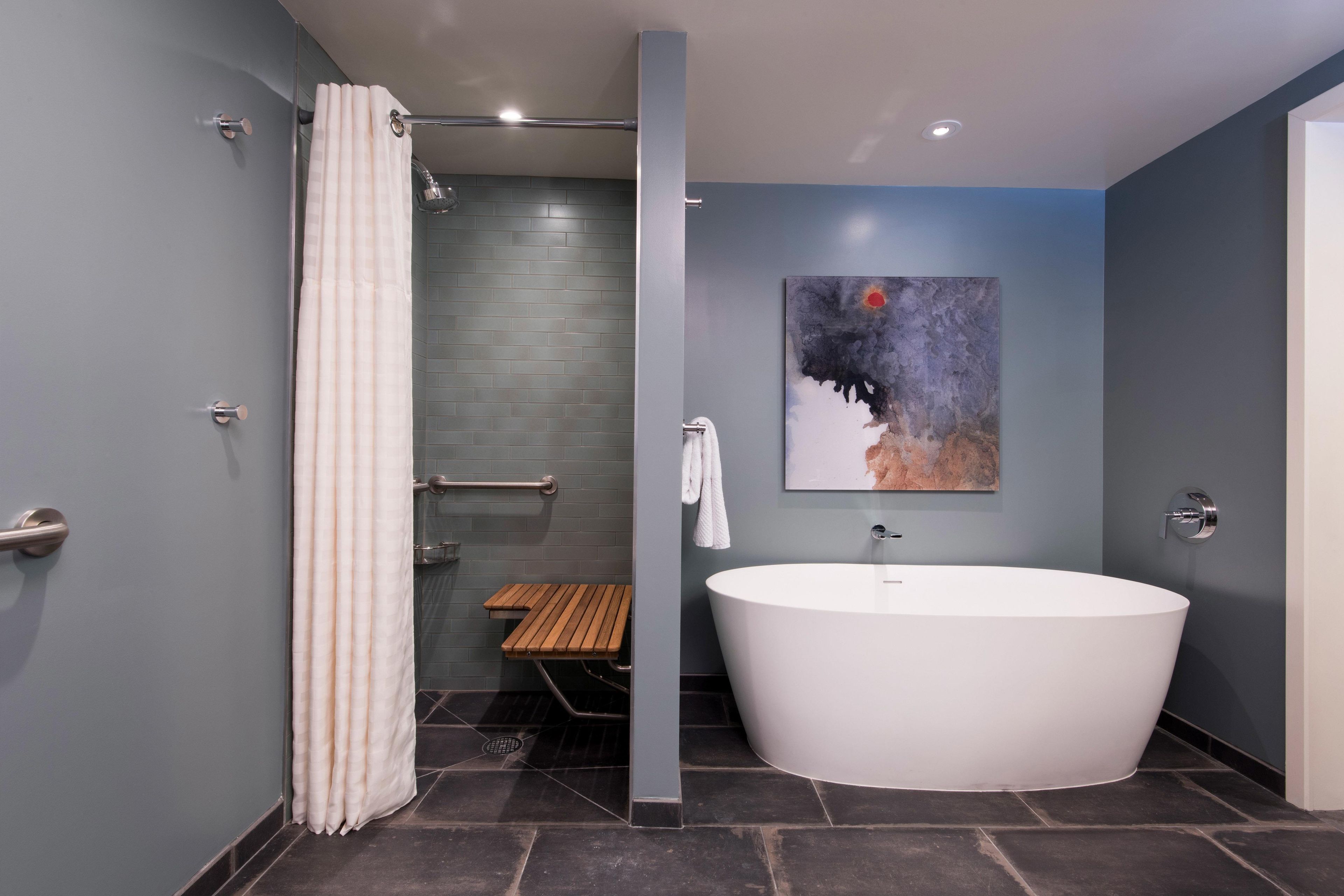 Une salle de bain moderne avec une baignoire sur pieds, un espace douche et un banc en bois.