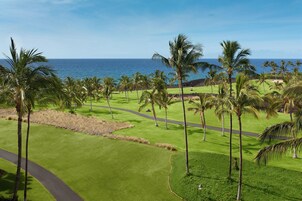 A golf course with a view of the ocean and palm trees.