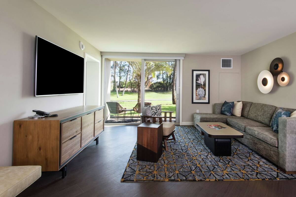 Un salon moderne avec un téléviseur à écran plat, un canapé, une table basse et un tapis à motifs.