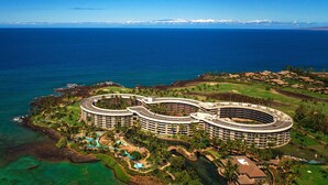 Un grande hotel a forma di cerchio, con numerosi piani, immerso nel verde e dotato di area piscina.