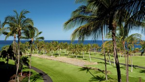 A golf course with a clear view of the ocean and palm trees. - Hilton Grand Vacations Club Ocean Tower Waikoloa Village (Waikoloa)