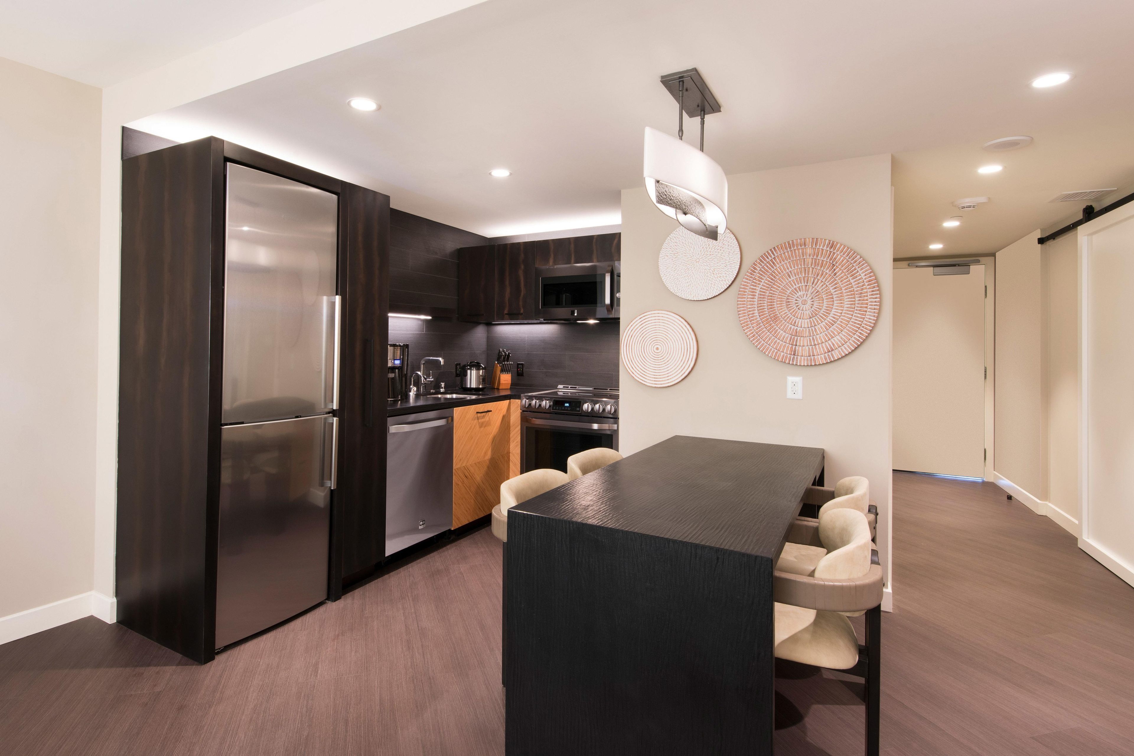 A modern kitchen with dark cabinetry, stainless steel appliances, and a central island with seating.