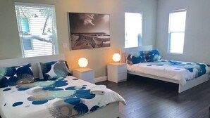 Un dormitorio con dos camas, una mesita de noche, una lámpara y un cuadro en la pared.