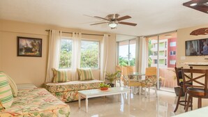 A spacious living room with a sofa, a coffee table, and a dining area with chairs. - Ocho Rios Vacation - Apartment (Ocho Rios)