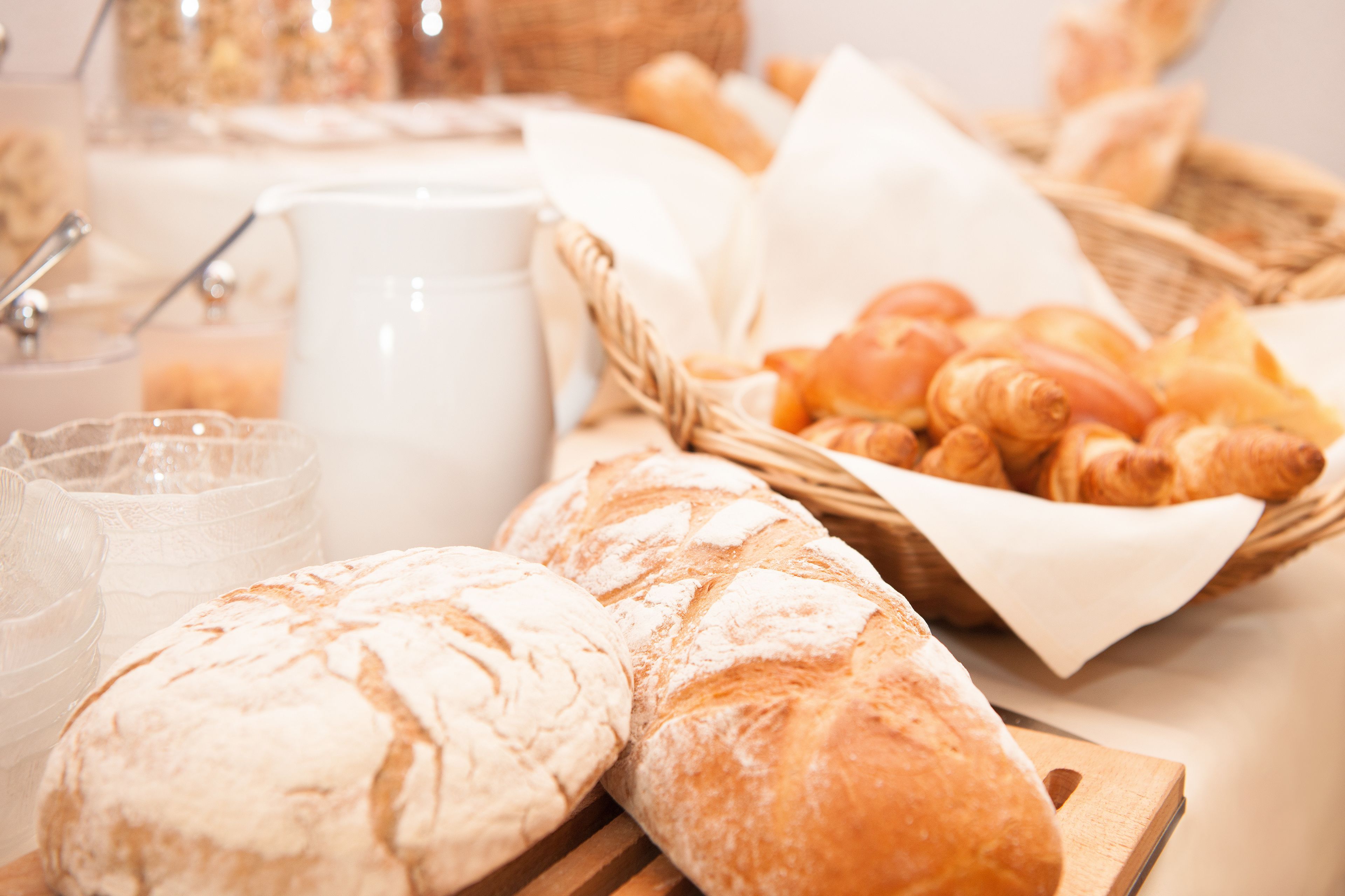A breakfast setting with bread, croissants, and a coffee pot.