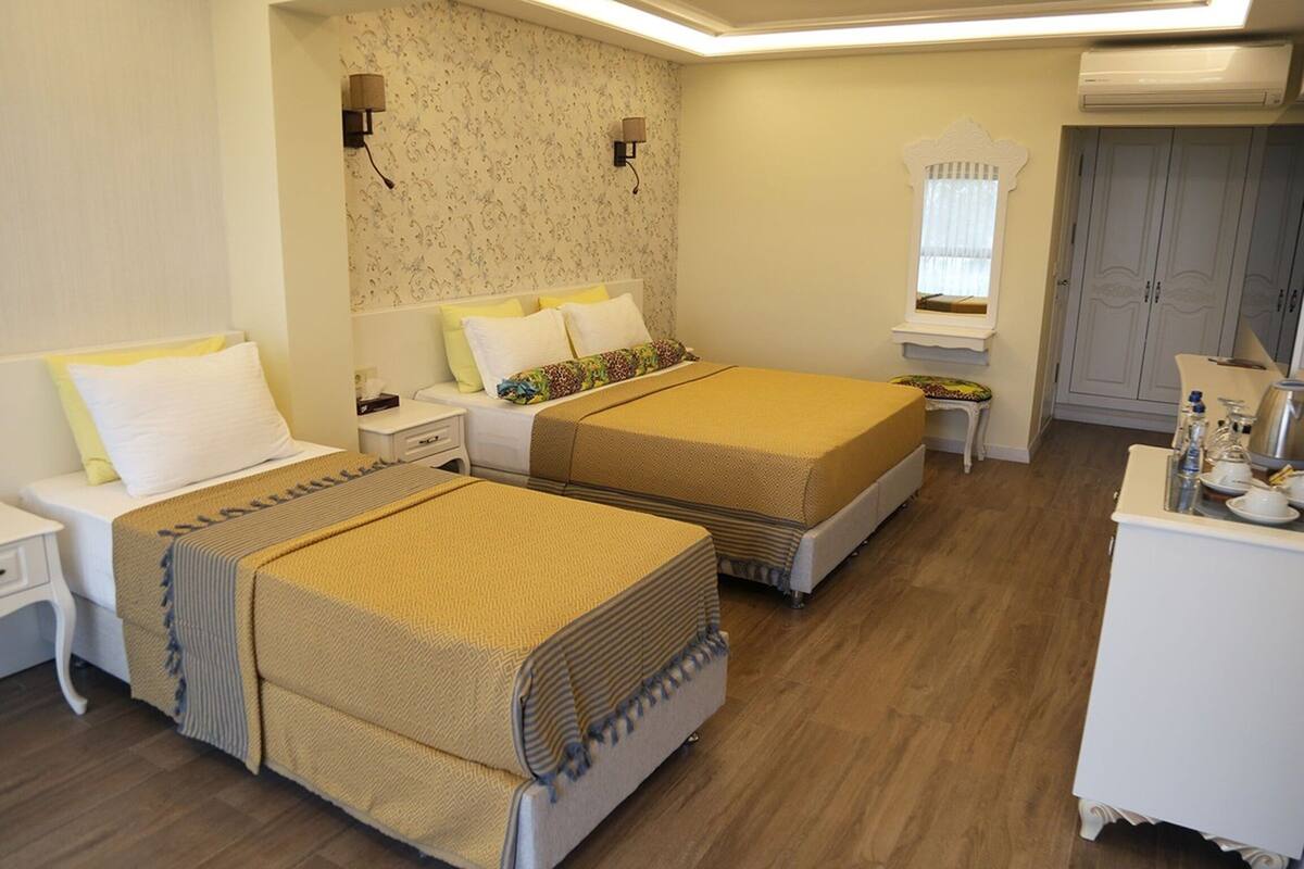 Ein Hotelzimmer mit zwei Betten, einem Nachttisch, einem Kleiderschrank und einem kleinen Schreibtisch mit Stuhl.