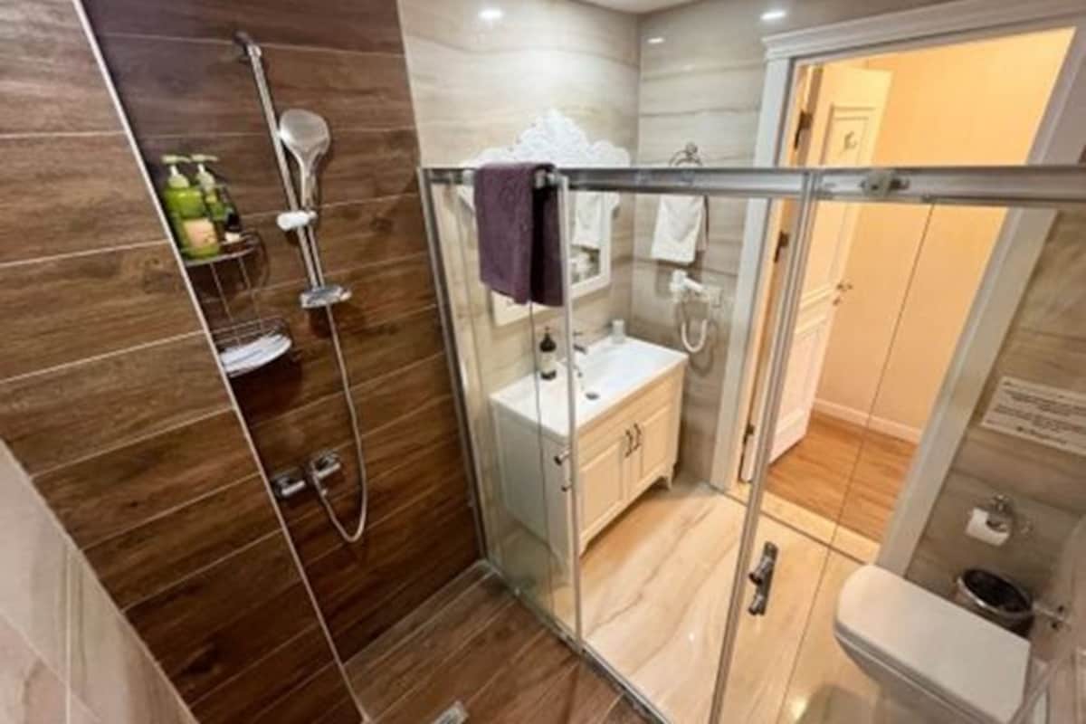 A modern bathroom with a glass shower enclosure, a white sink, and a toilet.