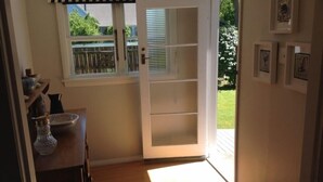 Ein Zimmer mit einer Schiebetür, die auf einen Balkon führt, einem Holzboden und einer Wand mit gerahmten Bildern.