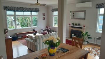 A spacious living room with a fireplace, a dining area with a wooden table, and a sofa.