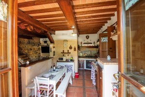Una cucina rustica con travi in legno, una parete in pietra e un'area pranzo con tavolo e panche.