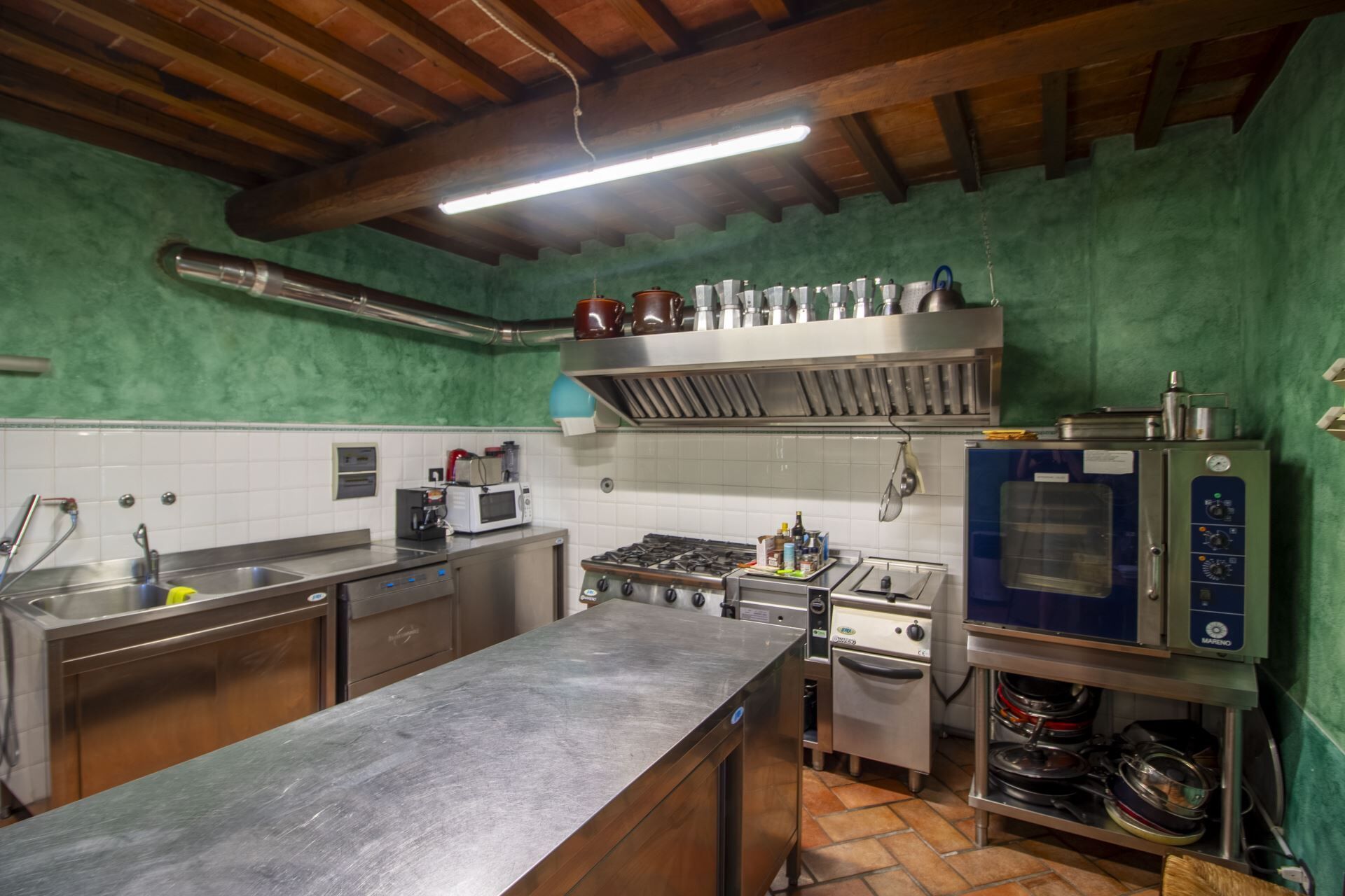 A kitchen with stainless steel appliances, a sink, and a tiled backsplash.