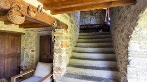 Eine rustikale Steintreppe, eine hölzerne Bank und eine Tür in einem raumhohen Mauerwerk.