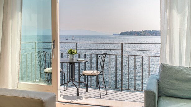 Ein Balkon mit Meerblick, einem Tisch mit Stühlen und einer Couch.