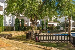 A courtyard with a pool, surrounded by trees and a stone wall.