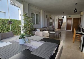 A modern living room with a sofa, dining table, and a staircase leading to another level.