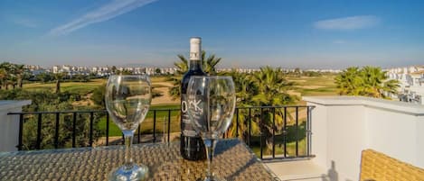 A balcony with a table, two wine glasses, and a bottle of wine.
