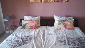 A bedroom with a bed, two pillows, a nightstand, and a lamp.