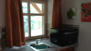A small kitchen with a window, a sink, and wooden cabinets.