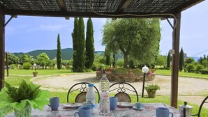 An outdoor dining area with a table set for two, surrounded by greenery and a stone wall. - PODERE MARCIGLIANO - CORITO (Cortona)