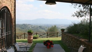 Eine Terrasse im Freien mit Tisch und Stühlen, einer Steinmauer und Blick auf die Landschaft.
