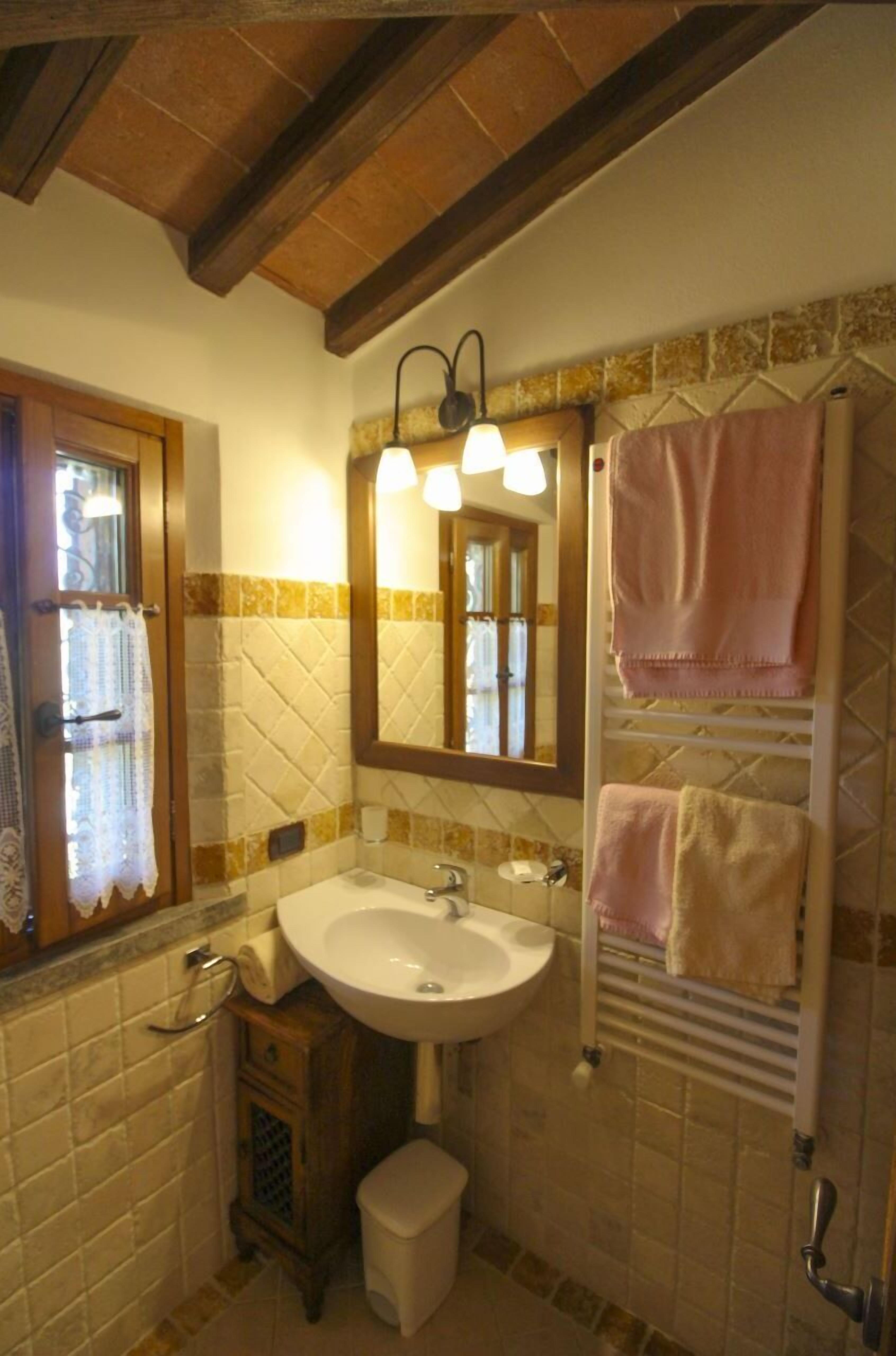 A bathroom with a sink, mirror, towel rack, and a small cabinet.