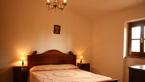 Ein Schlafzimmer mit einem hölzernen Bett, zwei Nachttischlampen, einer Chandelierleuchtre und einem Fenster mit Blick.