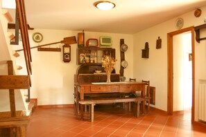 A dining area with a wooden table and benches, a wall clock, and a vintage radio. - Fully detached and fenced stone cottage with an outside porch. Garden equipped with table, chairs, d (Castiglion Fiorentino)
