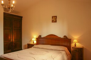 Une chambre à coucher avec un lit en bois, deux lampes de chevet, un lustre et un tableau au mur.