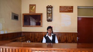 A reception desk with a sign reading "RECEPTION" and a clock above it. - Batian Grand Hotel (Nyeri)
