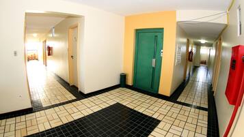 A corridor with a tiled floor, a green door, and a red fire extinguisher.