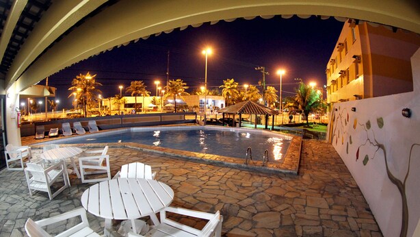 Un área de piscina al aire libre con sillones de descanso y un pequeño pabellón.