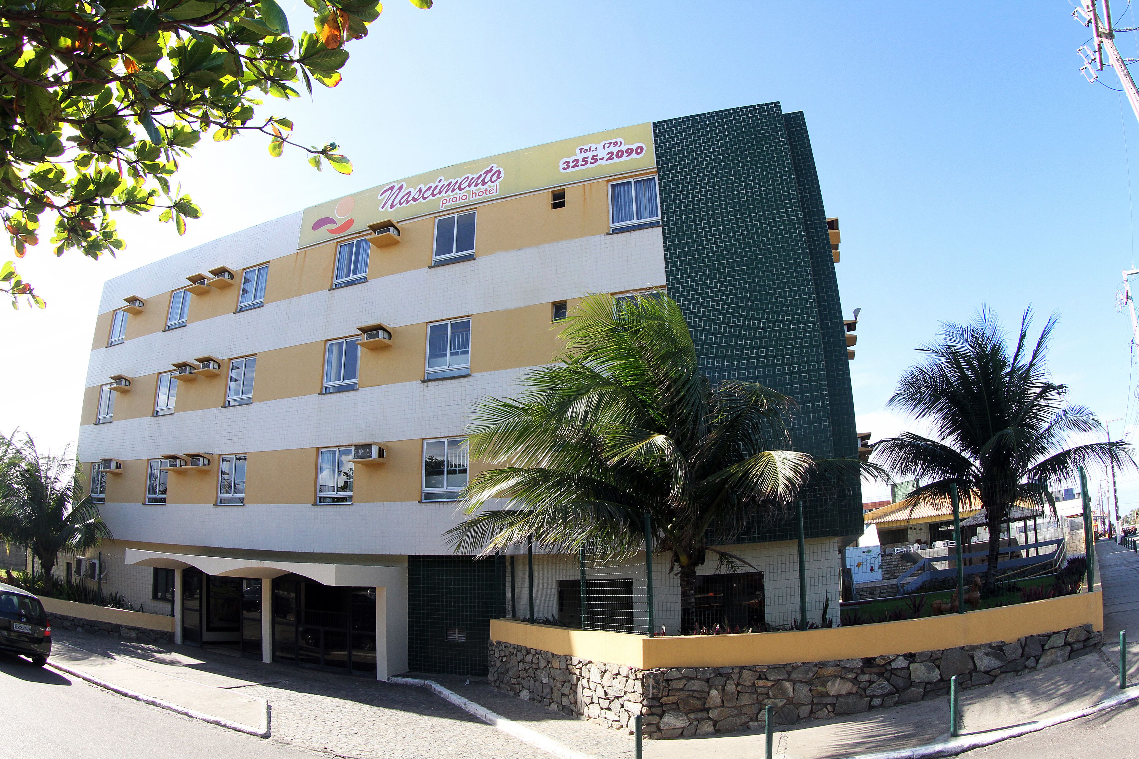 Um hotel de vários andares com fachada amarela, diversas varandas e base de pedra.