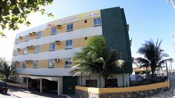 Um hotel de vários andares com fachada amarela, diversas varandas e base de pedra.