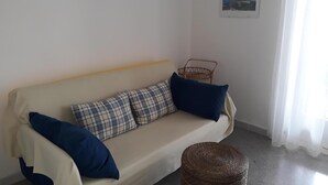 Un canapé beige agrémenté de coussins bleus et à carreaux, un panier en osier et un tableau encadré accroché au mur.