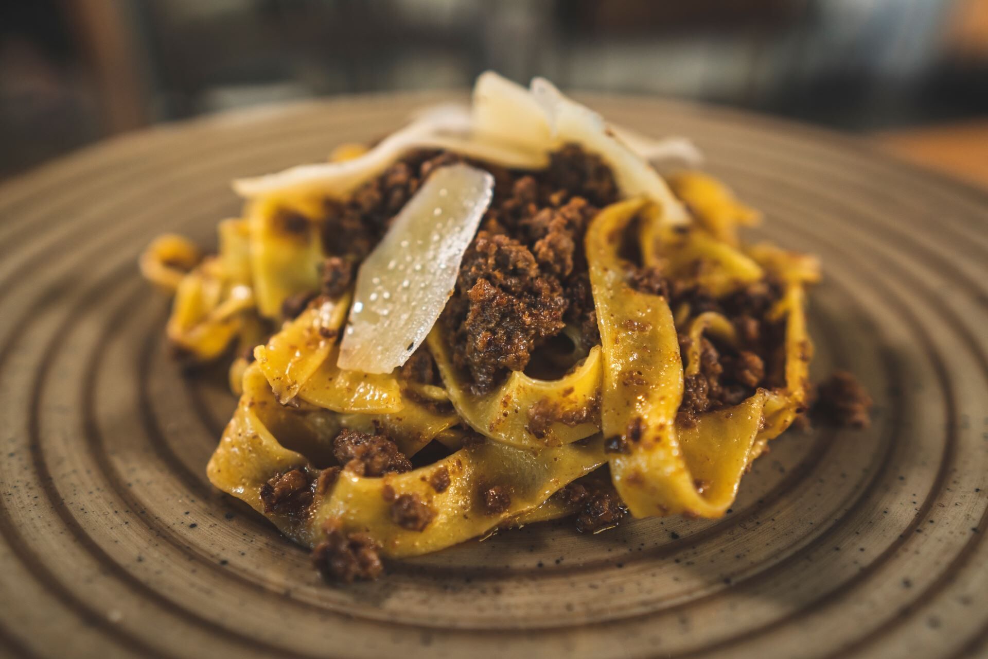 Lautasella on pastaa, jauhelihakastiketta ja juustoa, ja lautanen on valmistettu kuvioidusta keramiikasta.