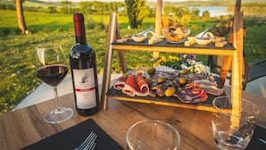A wooden table with a bottle of wine, glasses, and a charcuterie board with various meats and cheeses.