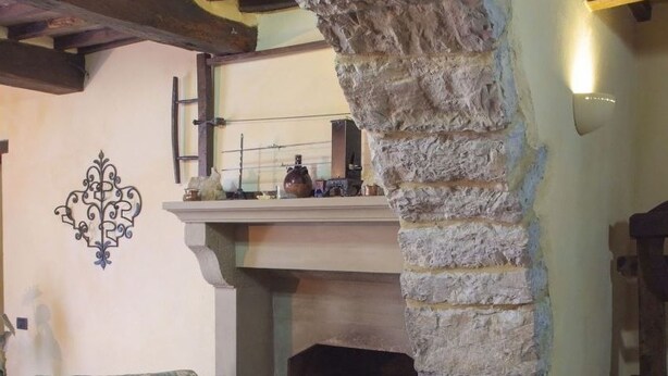 Una stanza con camino in pietra, un divano e un elemento decorativo a parete.