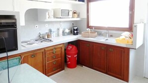 Una cuina petita amb armaris blancs, microones, cafetera i un rentaplat.