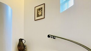 Una escala amb graons beix connectant amb un aterradís. Hi ha una barana metàl·lica al costat dret.