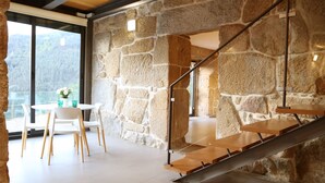 A modern interior with a stone wall, a staircase, and a dining area with white chairs and a table. - Private Pool with fantastic views over Douro River - Porto & Airport 1H (Marco De Canaveses)